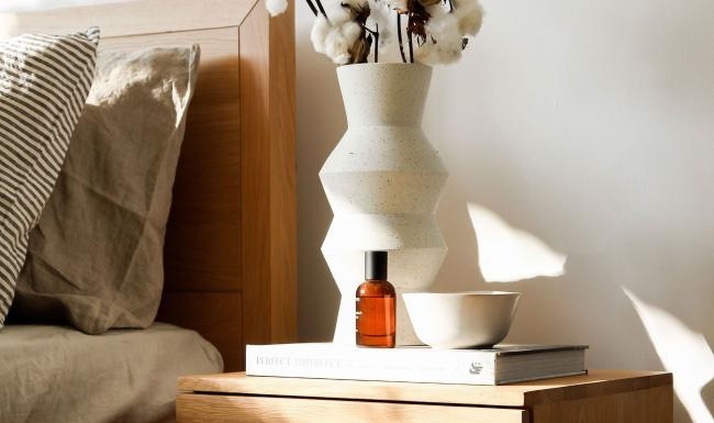 a vase with cotton stems on a bedside table